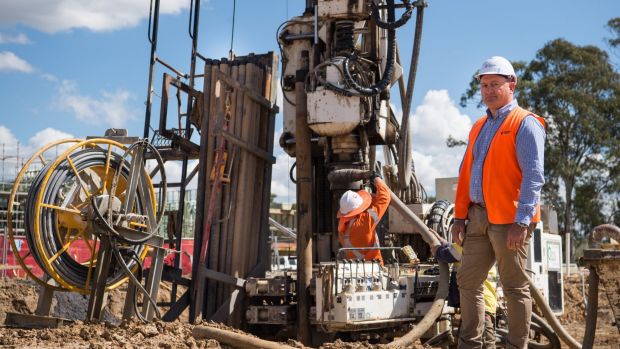 Fairwater construction manager Adam Chymiak with the rig that drills the geothermal pipelines.