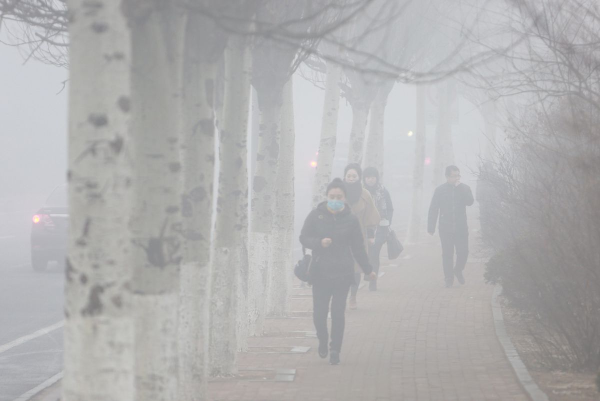 Pedestrians wearing masks walk along a street in heavy smog in Dalian, China.