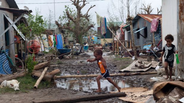 Young children walk through debris in Vanuata after Cyclone Pam hit in 2015.