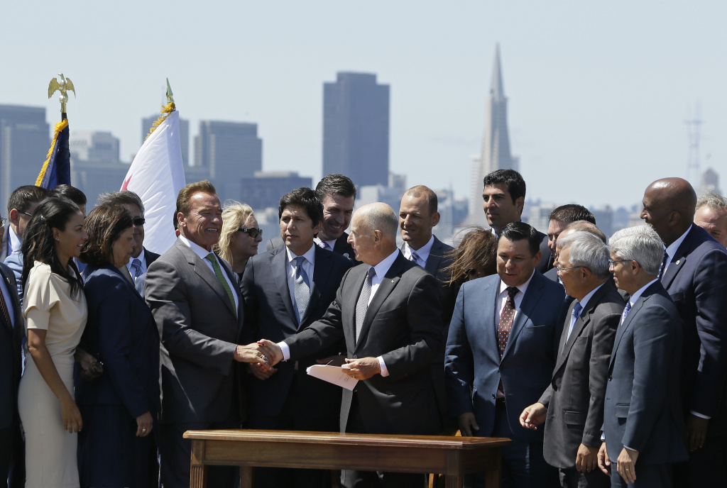 California Gov. Jerry Brown, right, shakes hands with former Gov. Arnold Schwarzenegger, left, after signing a climate bill on Treasure Island, Tuesday, July 25, 2017, in San Francisco. Gov. Brown signed legislation keeping alive California's signature initiative to fight global warming, which puts a cap and a price on climate-changing emissions. The Democratic governor was joined by his celebrity predecessor, Arnold Schwarzenegger, who signed the 2006 bill that led to the creation of the nation's only cap and trade system to reduce greenhouse gases in all industries.