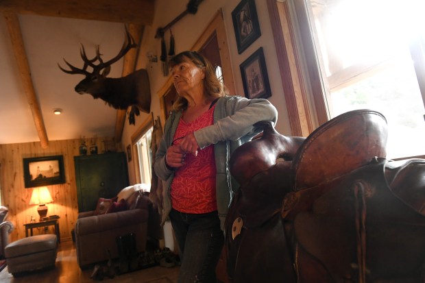 Longtime Colorado rancher Susan Robinson leans on the saddle belonging to her late-husband Larry inside her home on her ranch June 28, 2017 near Rifle.