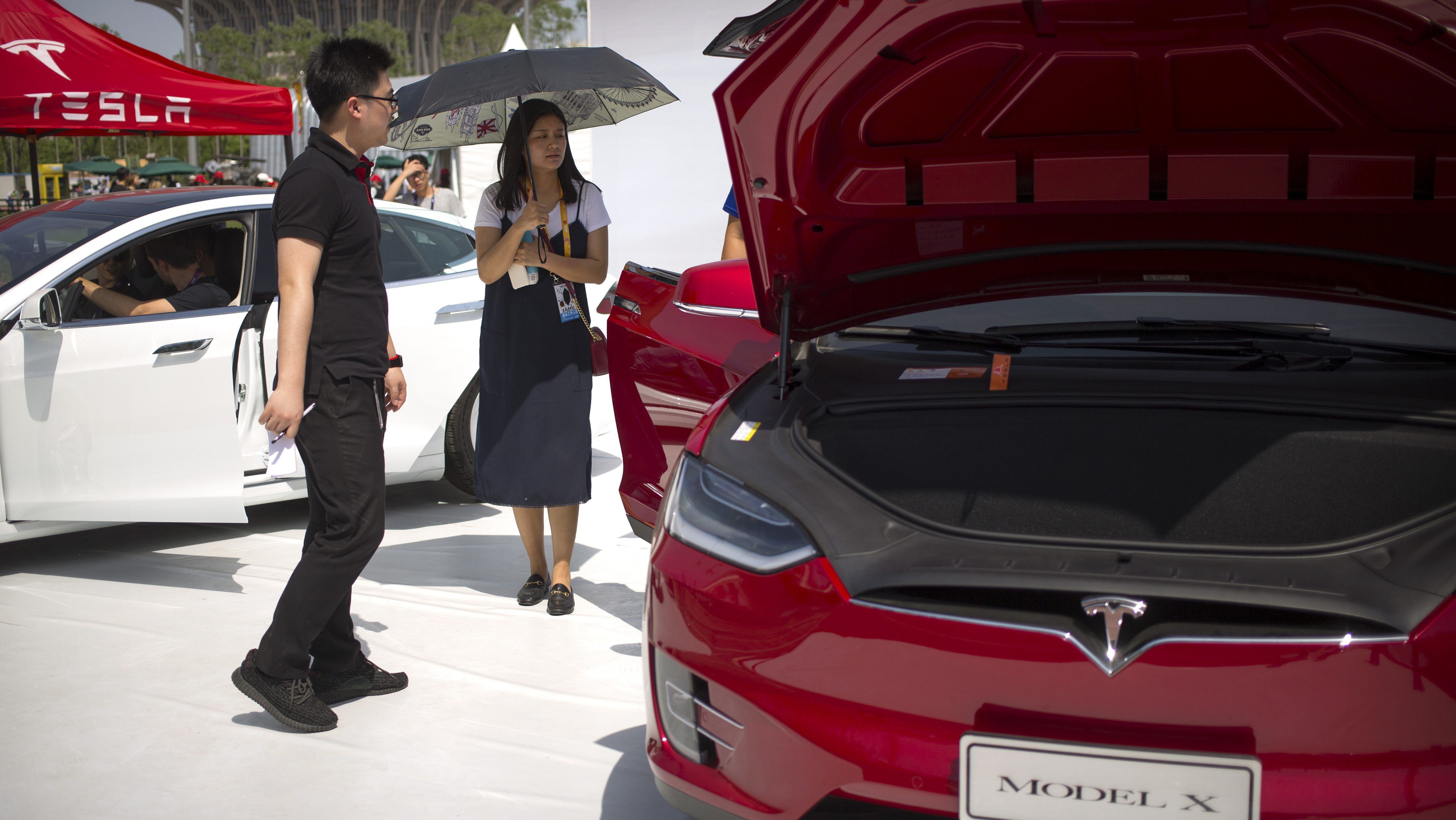 A visitor holds an umbrella as she looks at a Tesla Model X car on display at the G Festival, part of the Global Mobile Internet Conference (GMIC) in Beijing, Saturday, April 29, 2017. (AP Photo/Mark Schiefelbein)