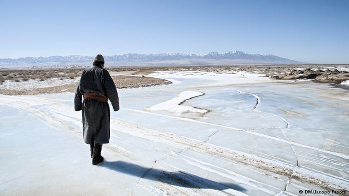 A herder walks on a patch of ice