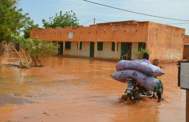 Un homme conduit sa moto dans une rue inond&eacute;e par des pluies torrentielles, &agrave; Niamey au Niger, le 15 juin 2017-AFP/Archives/BOUREIMA HAMA