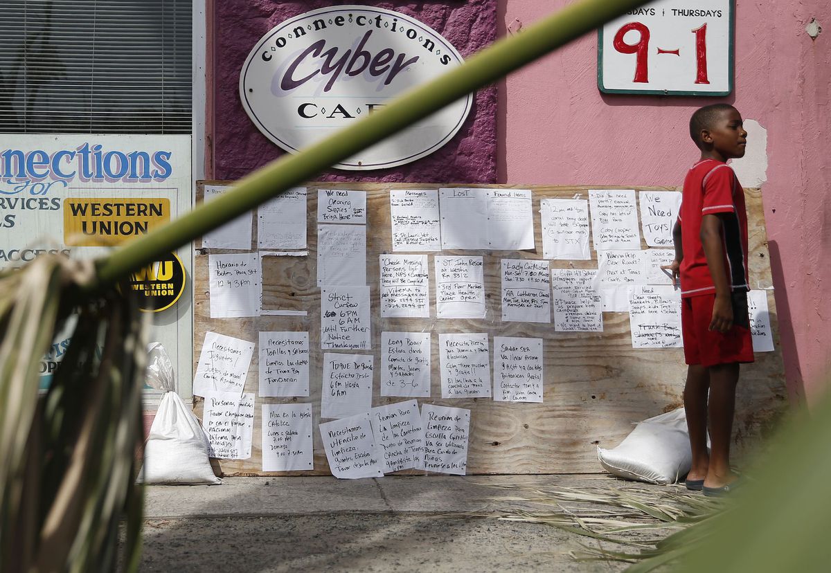 A boy stands beside a makeshift message board, of St. John in the US Virgin Islands on Sept. 12, 2017.