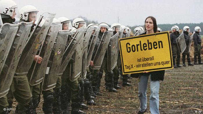 An anti-nuclear activist with sign walks past line of riot police in Gorleben, 1997 (AP)