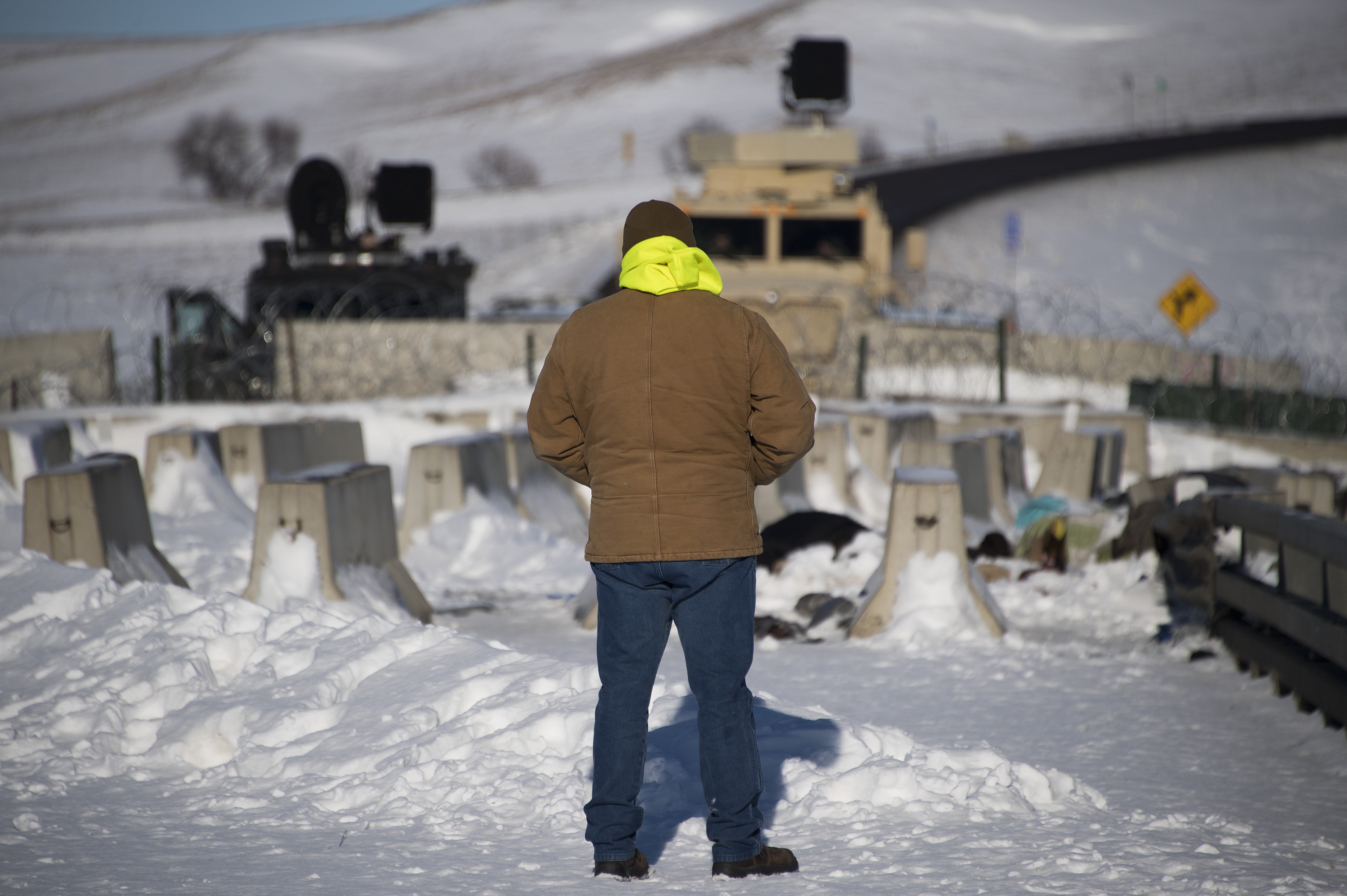 An activist stands alone in silent protest by a police barricade on a bridge near Oceti Sakowin Camp on the edge of the Standing Rock Sioux Reservation on December 4, 2016 outside Cannon Ball, North Dakota.Native Americans and activists from around the country gather at the camp trying to halt the construction of the Dakota Access Pipeline. / AFP / JIM WATSON (Photo credit should read JIM WATSON/AFP/Getty Images)