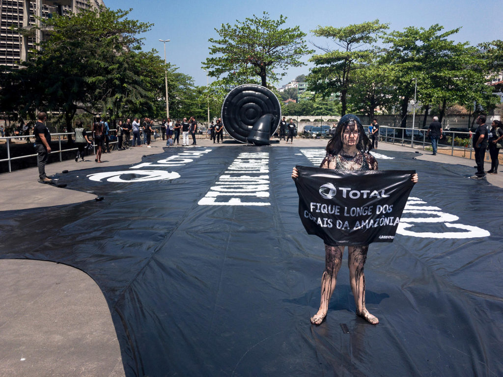 Rio de Janeiro, Rio de Janeiro, Brazil. 29th September 2017. People protest against oil and gas drilling in the Amazon. Greenpeace activists dressed in black and covered in oil hold banner asking French Oil major Total not to put its gain before the planet and stay away from the Amazon reefs. Credit: Ellen Pabst dos Reis / Alamy Stock Photo. KBRTBA