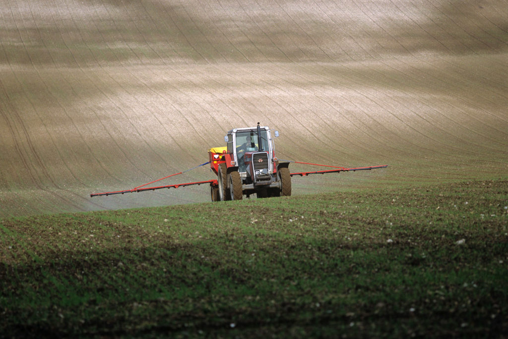Spreading fertiliser granules on a young barley crop. Credit: Nigel Cattlin / Alamy Stock Photo. BGDJR5 