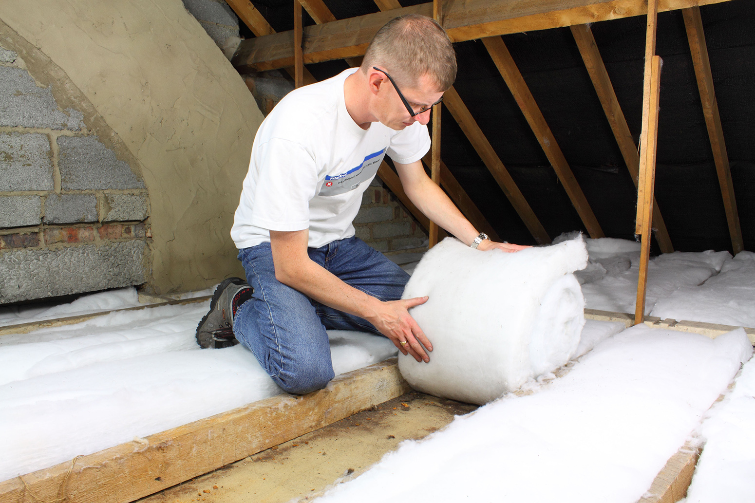 BR10FX Man laying loft insulation in attic roofspace. Image shot 09/2010. Exact date unknown.