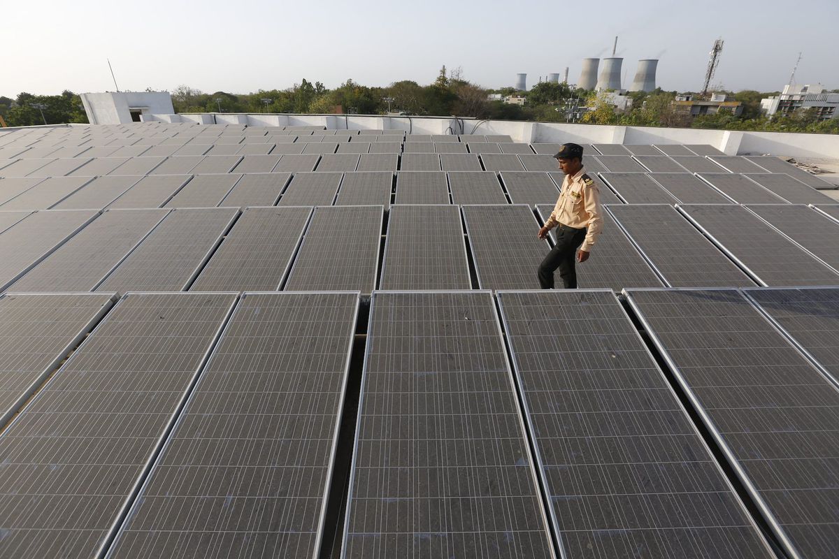 An Indian security guard walks amid a rooftop solar plant in Gandhinagar, India. An Indian security guard walks amid a rooftop solar plant in Gandhinagar, India.