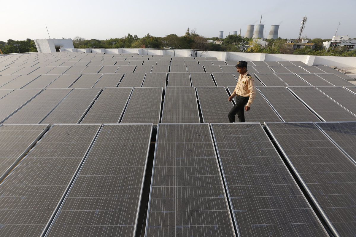 An Indian security guard walks amid a rooftop solar plant in Gandhinagar, India.