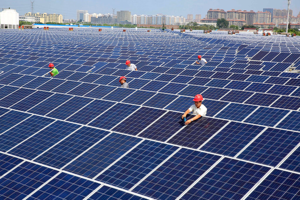 Workers install solar panels on the rooftop of a textile factory in Nantong, China. Credit: Imaginechina Limited / Alamy Stock Photo. W83K69